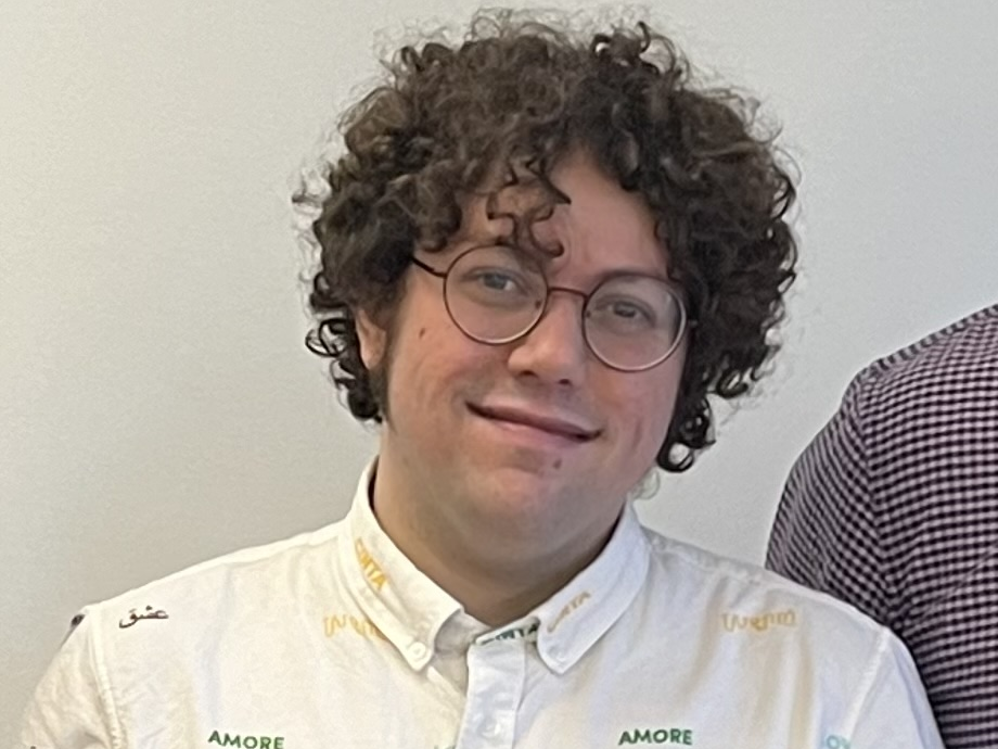 BrettC in a white collared shirt with the word "love" in several different languages on it